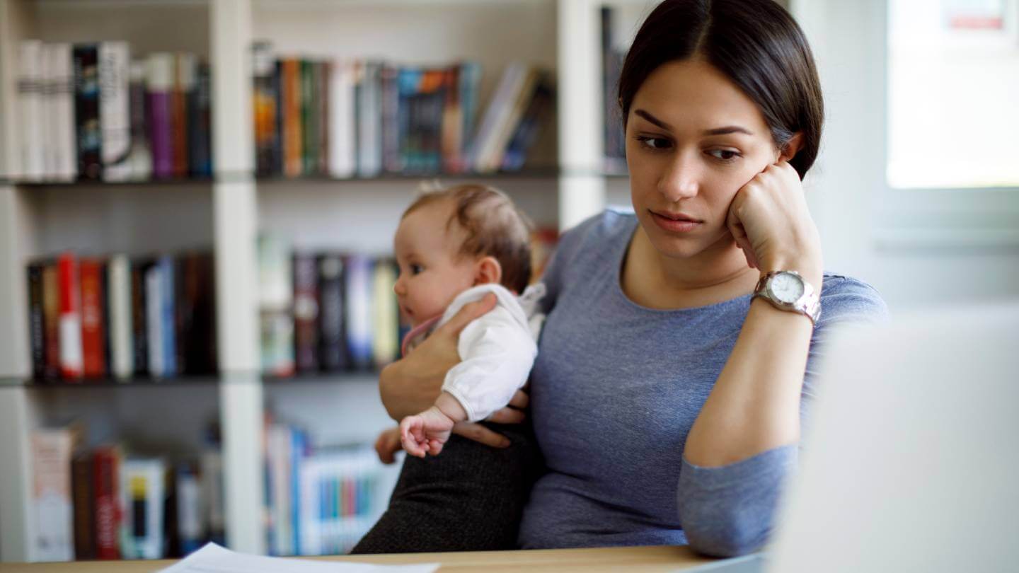 Worried woman on computer with baby on her lap