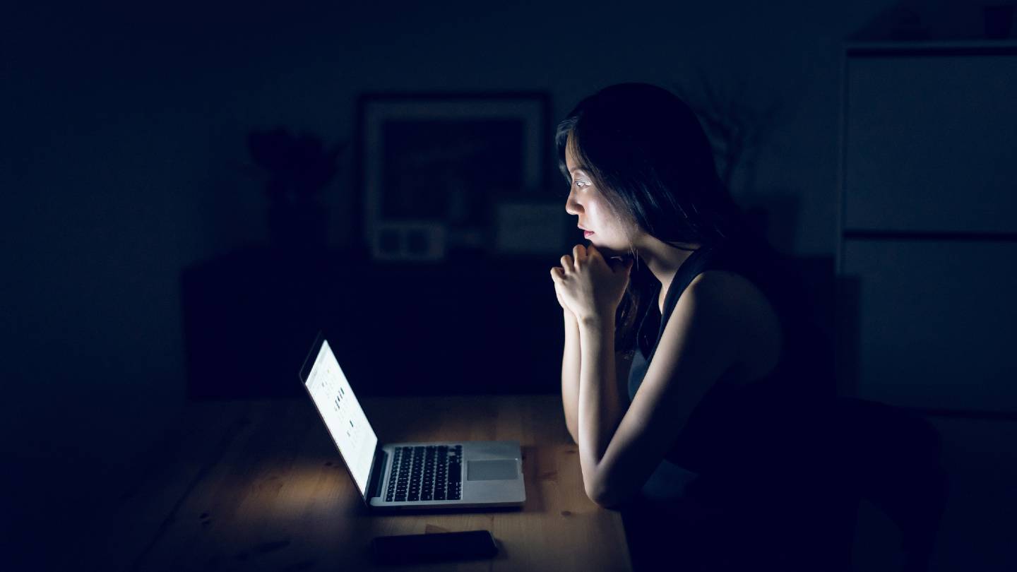 Woman staring at her computer in the dark