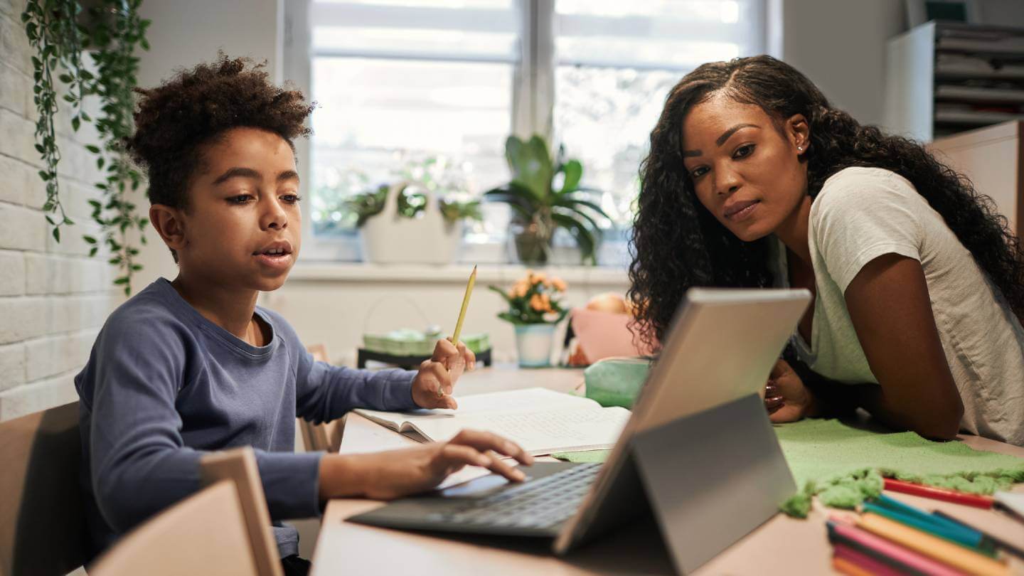 Woman assisting child with online homework