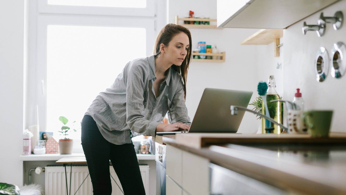 Woman looking at laptop on kitchen counter