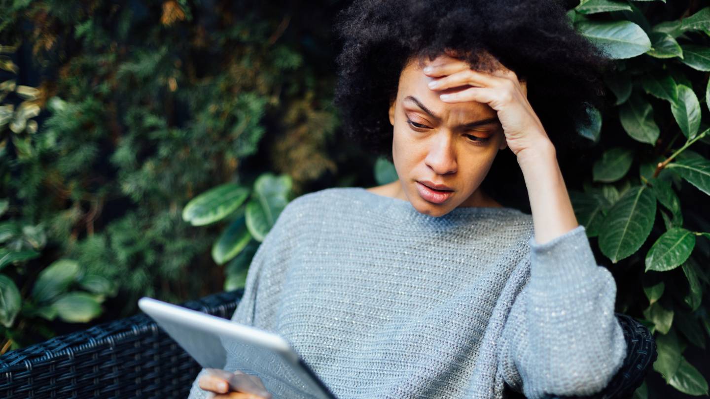 Young African American woman reading bad news on her mobile device