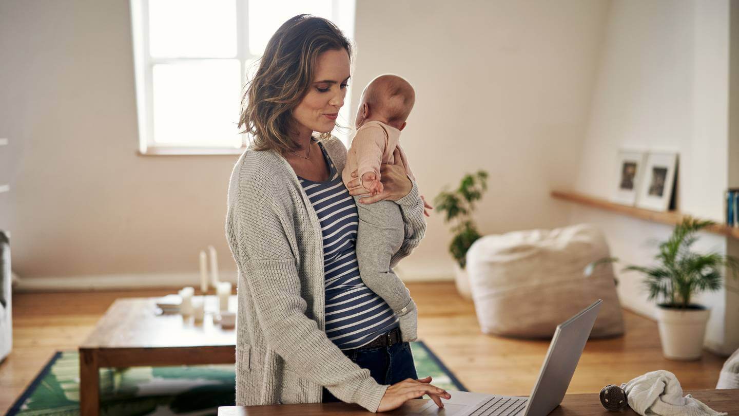 Woman using computer while holding a baby