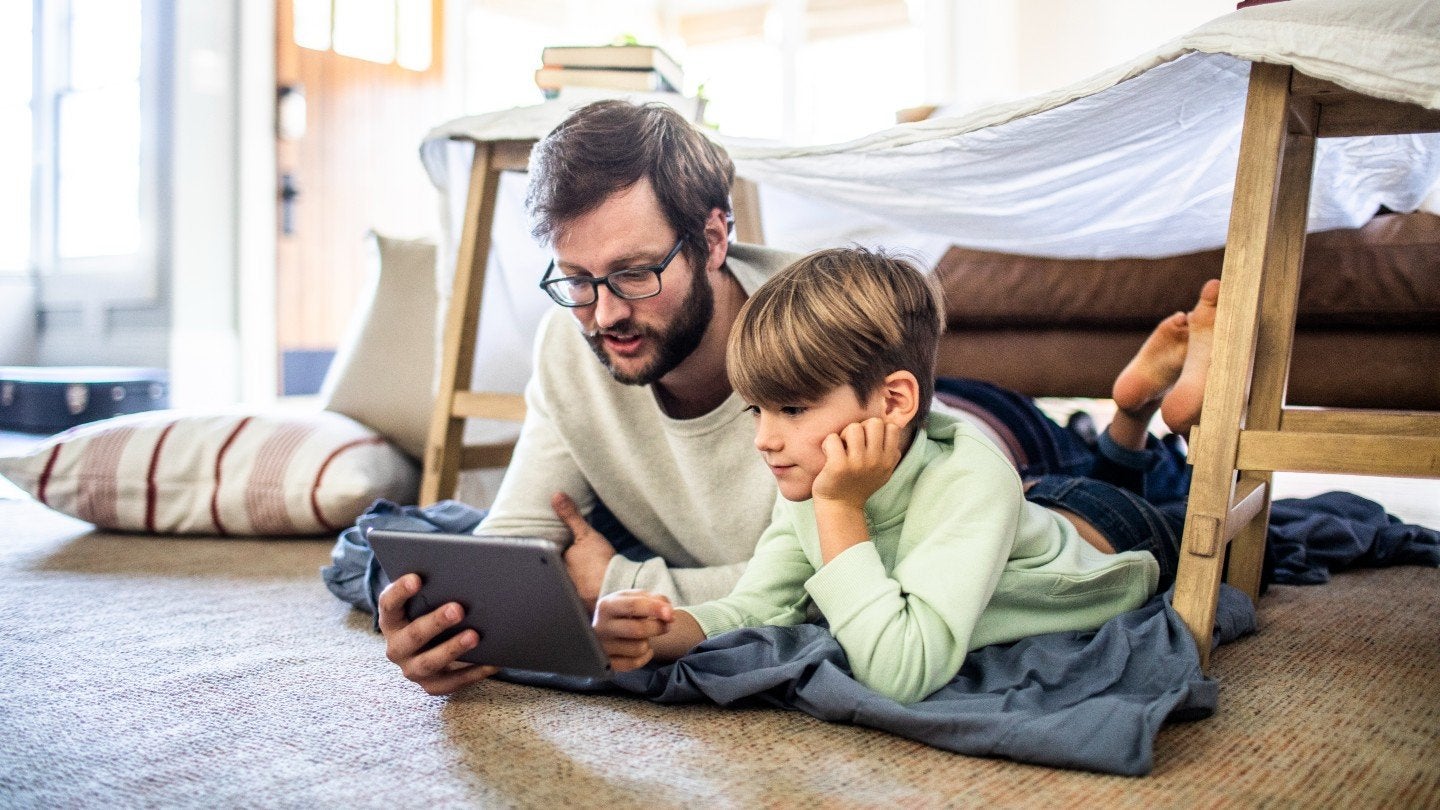 Adult and child watching a tablet.