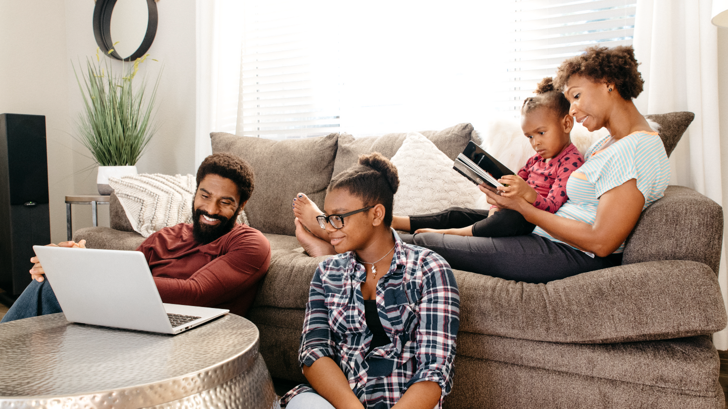 family gathered together in living room using laptops and tablets