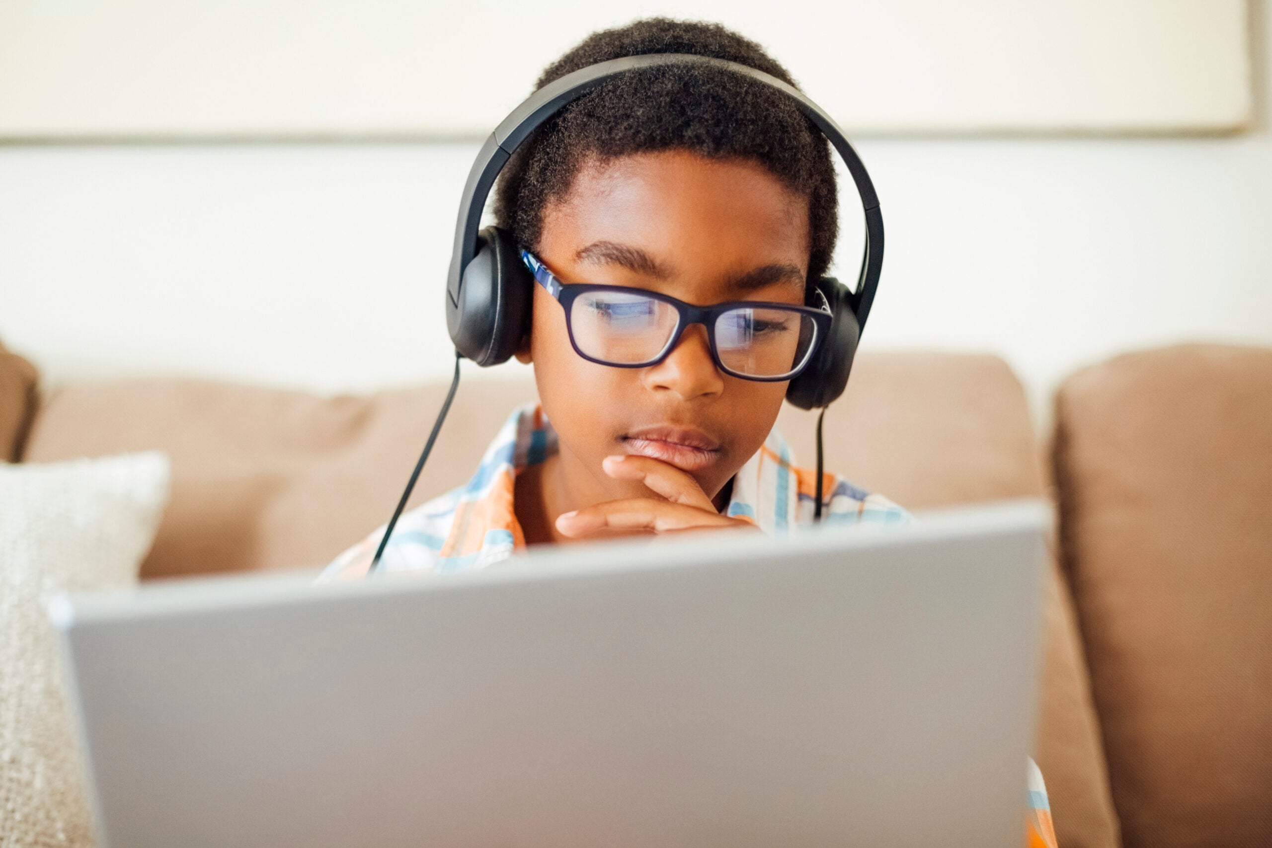 Boy with headphones using laptop in living room